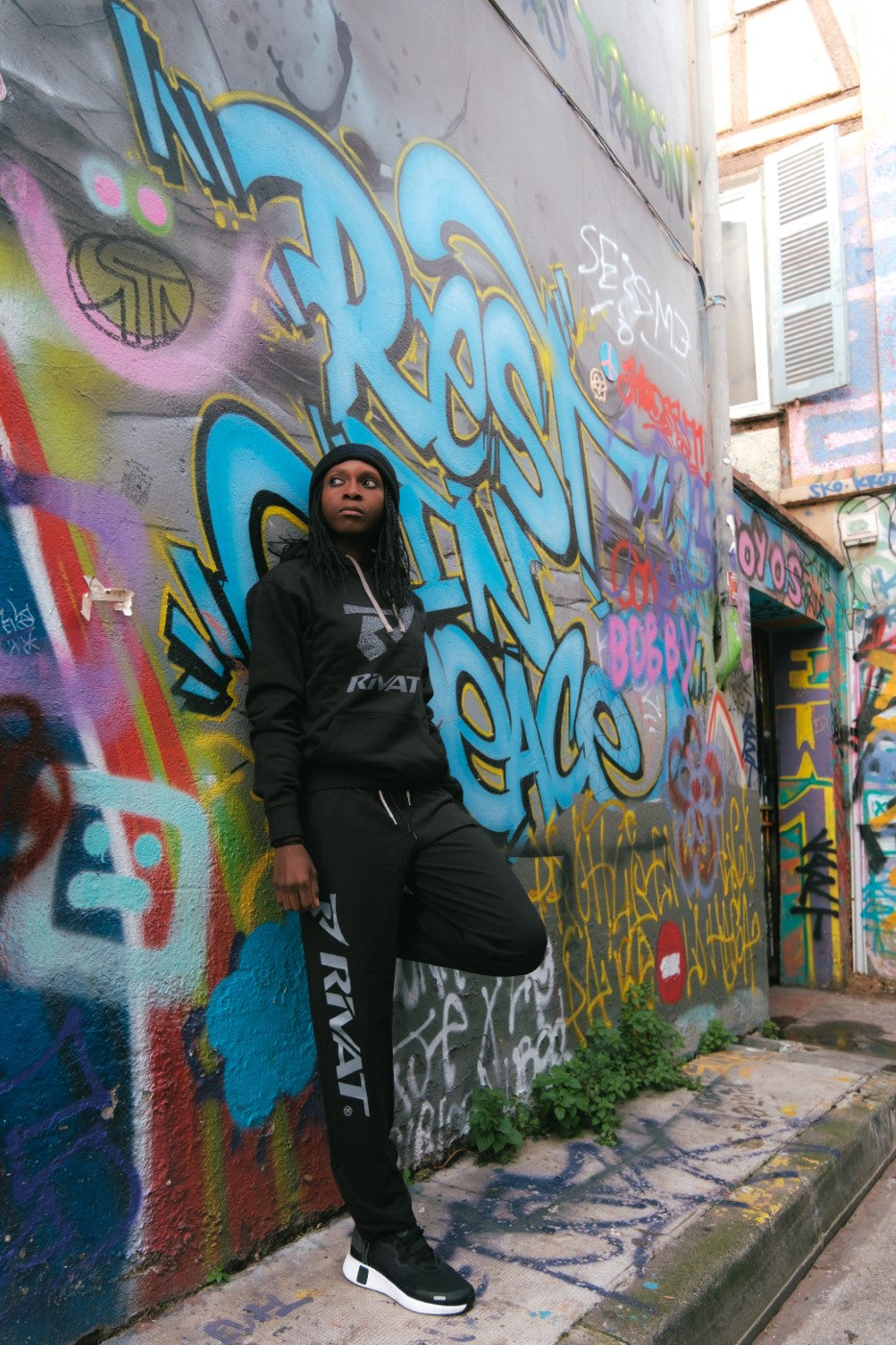 Modèle portant des vêtements de sport Rivat devant un mur coloré de graffiti urbain