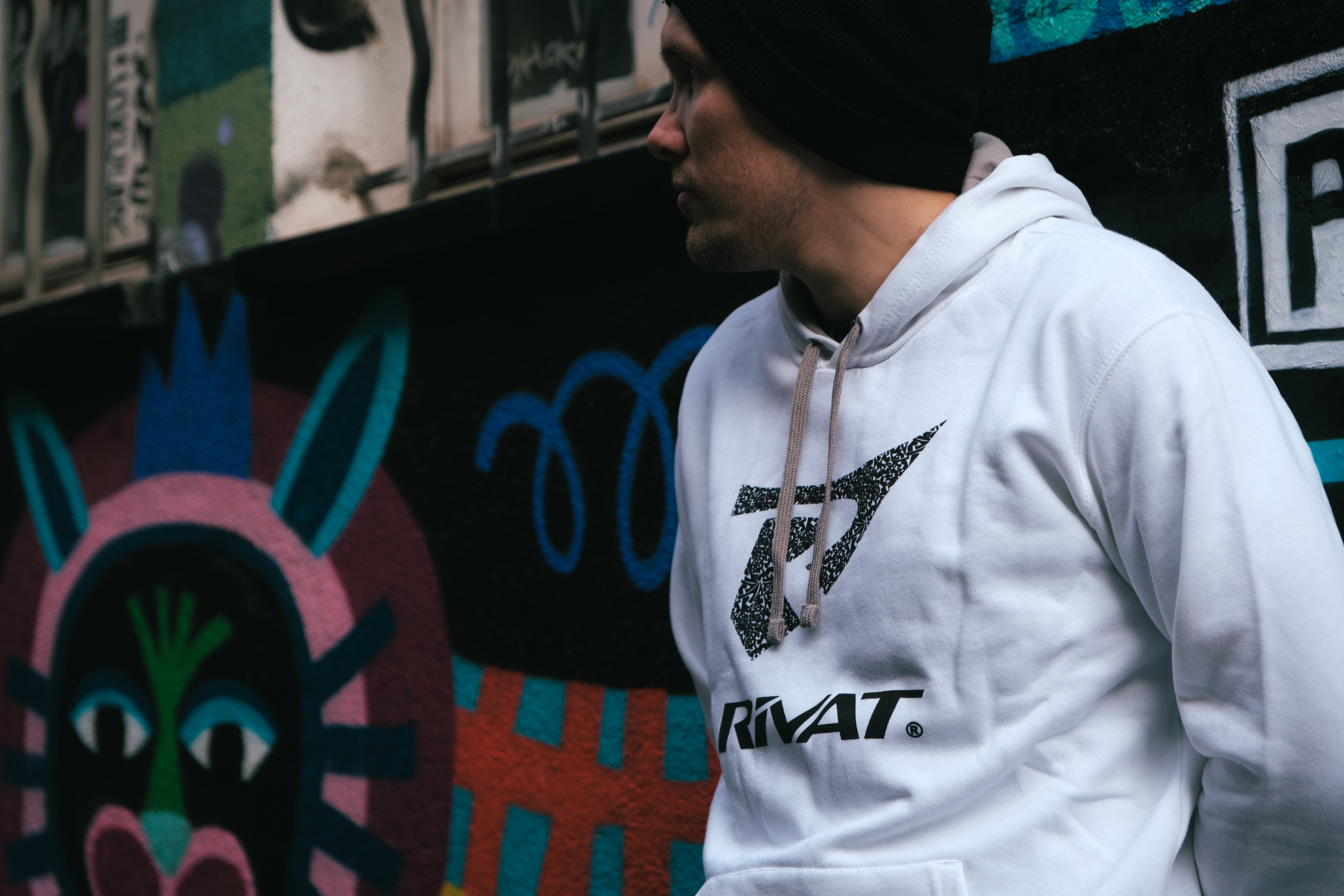 Homme portant un sweat à capuche blanc de la collection t-shirts & sweats sport près d'un mur coloré