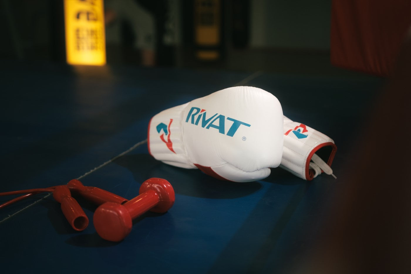 Gants de boxe RIVAT posés sur un ring avec corde à sauter rouges pour chaussures de boxe française confirmés