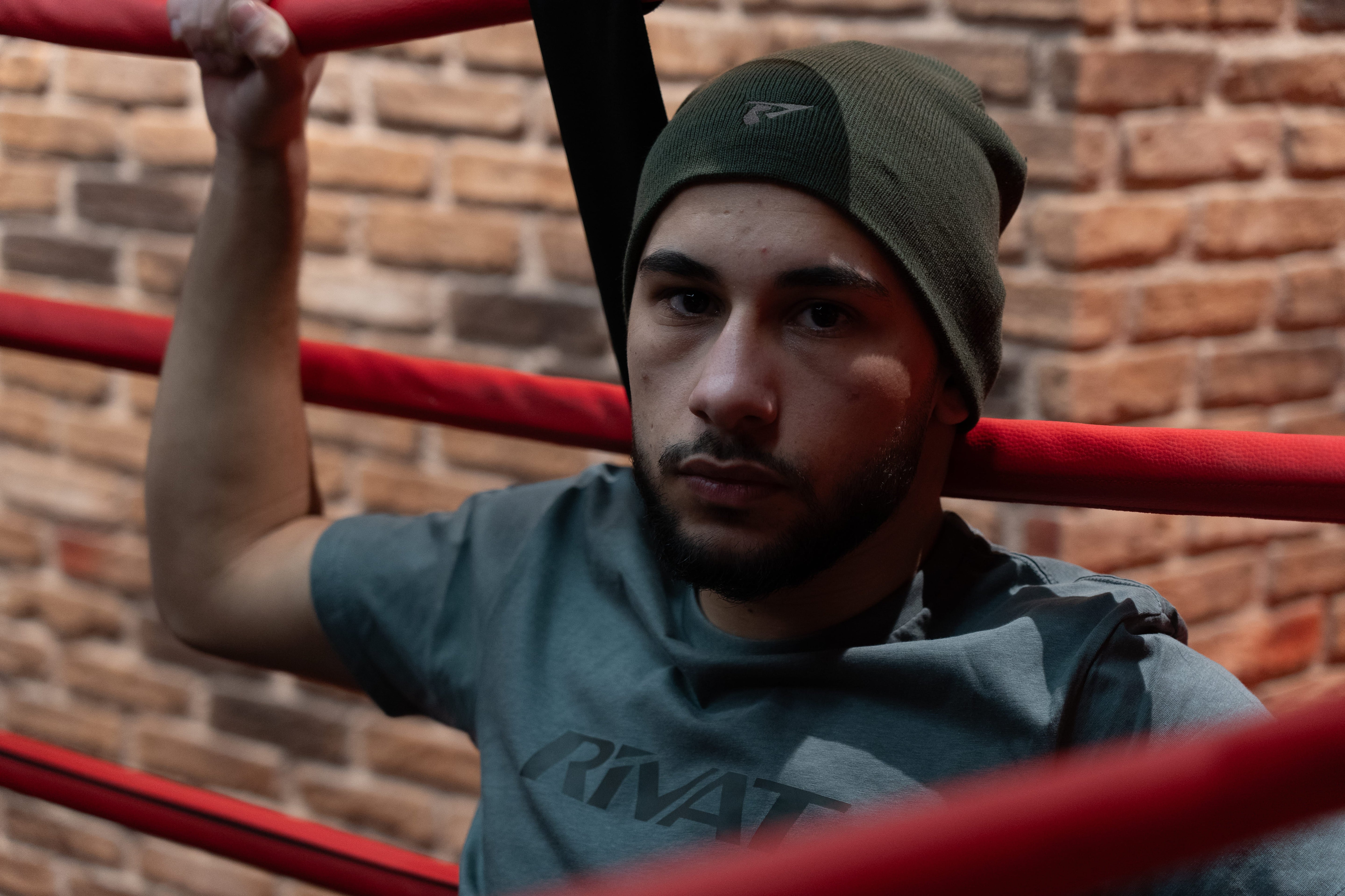Homme portant textile sport homme avec t-shirt et bonnet assis dans un ring de boxe