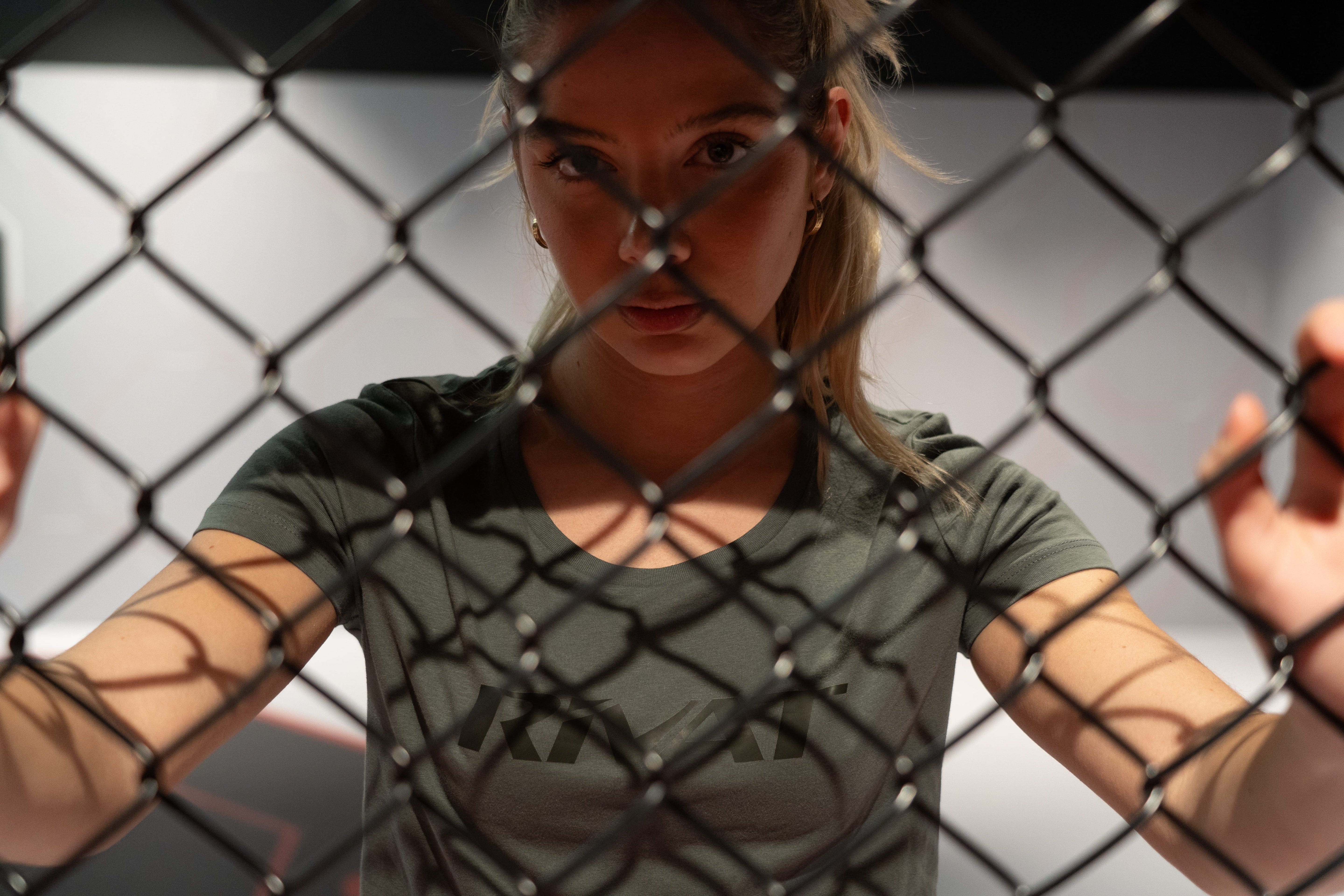 Femme portant un t-shirt de textile sport femme moderne et confortable derrière une grille de cage
