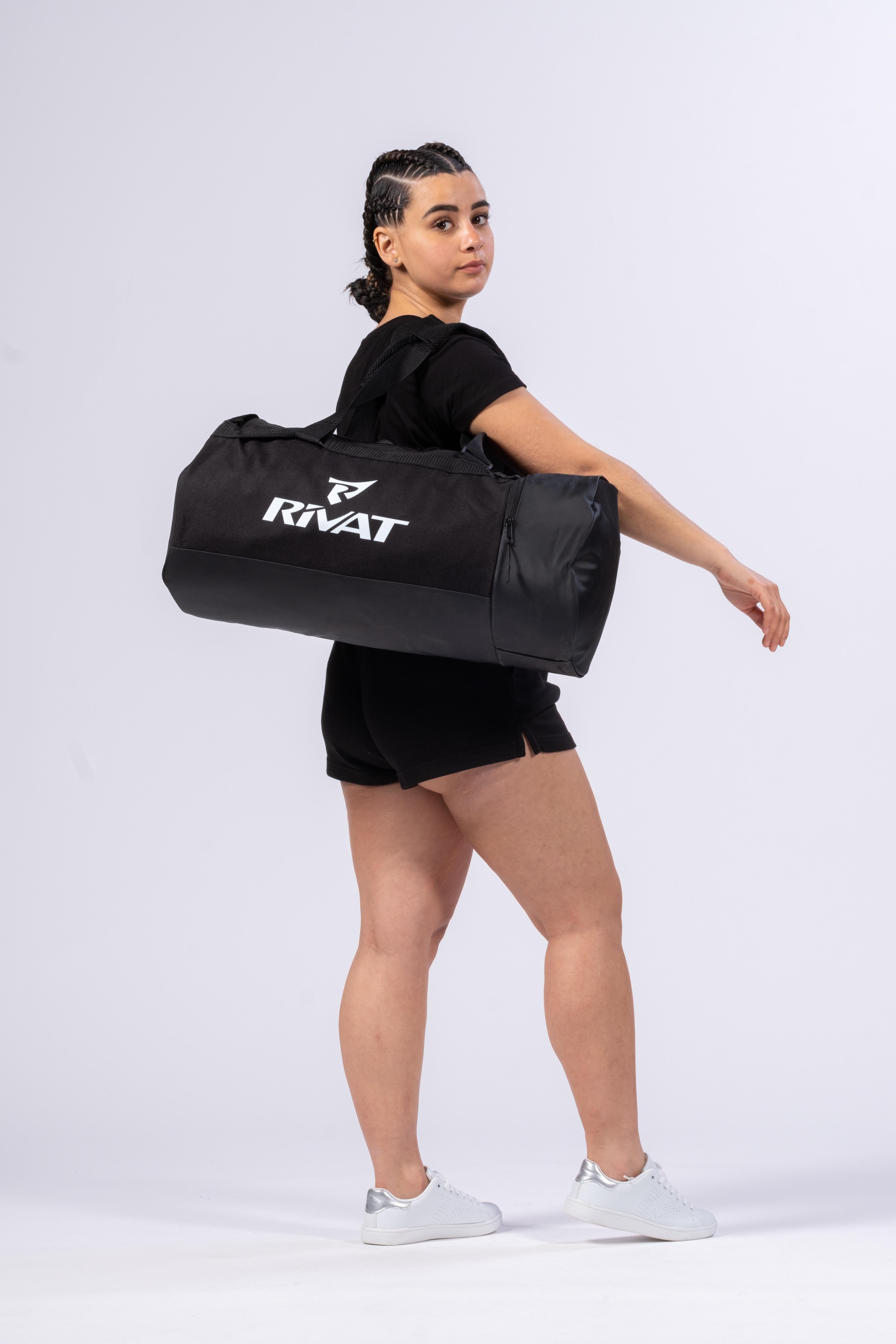 Sac de sport 40L homme Rivat noir porté à l'épaule par une femme en tenue de sport