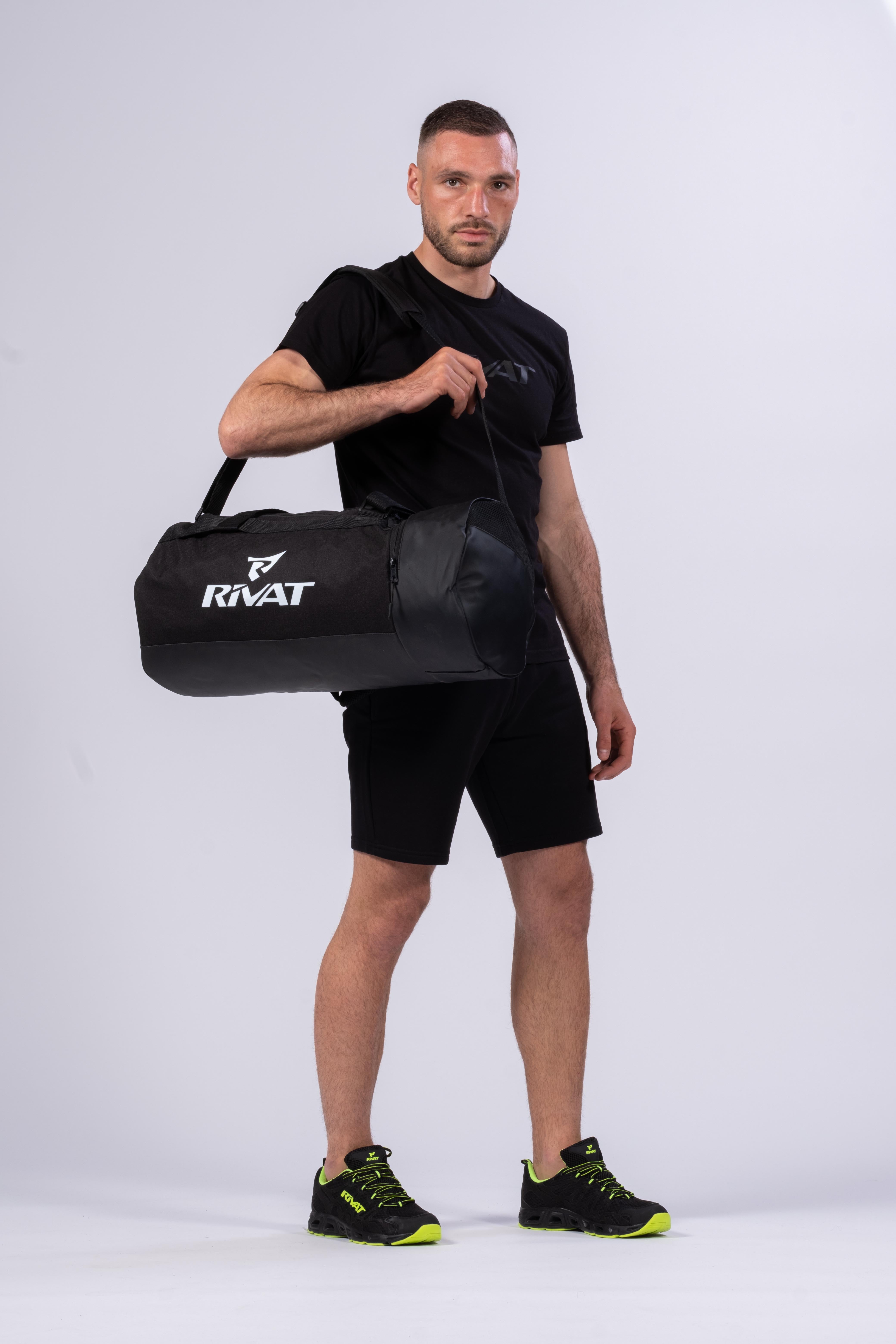Homme portant un sac de sport 40L homme Rivat noir avec logo blanc et bandoulière réglable