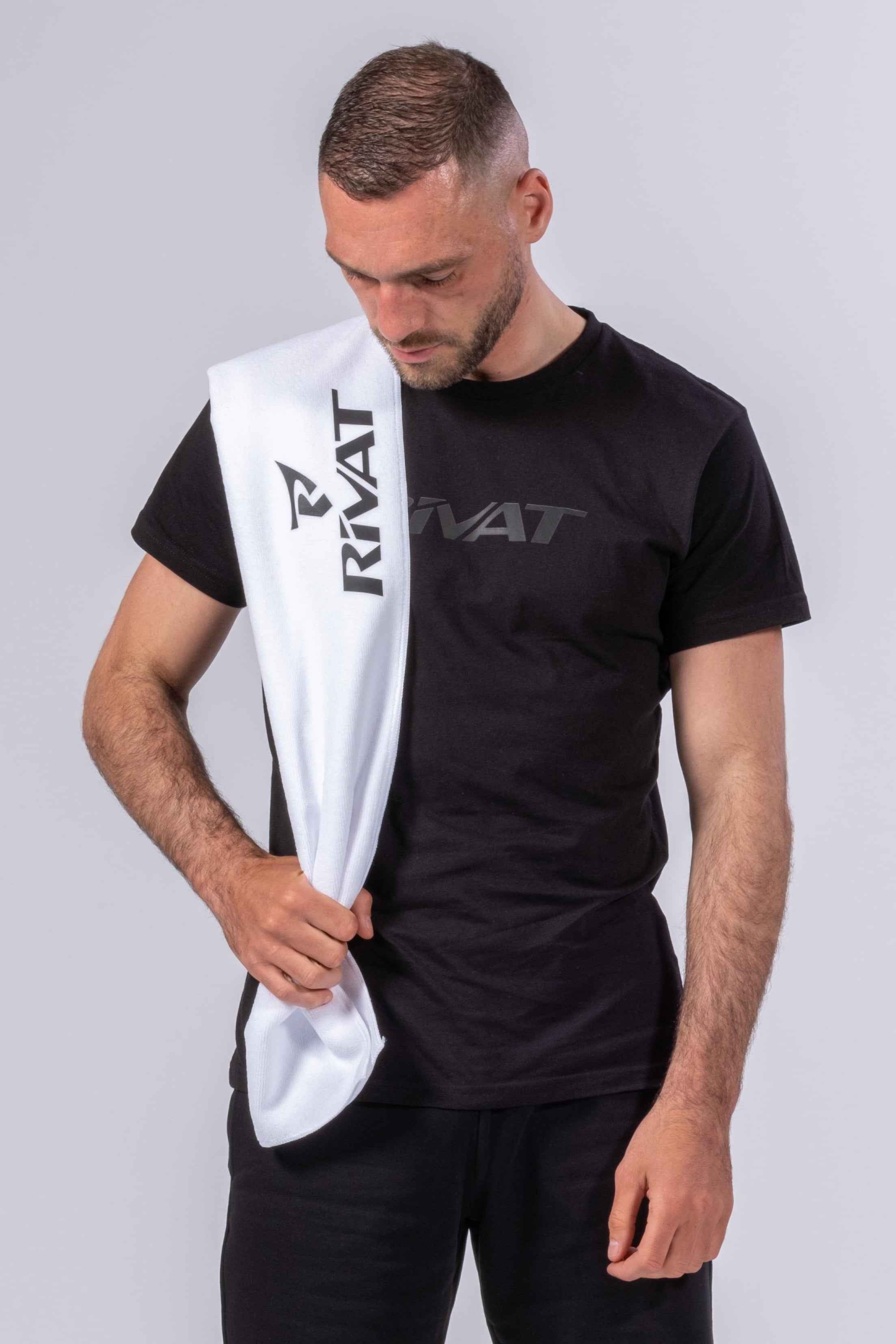 Homme portant une serviette microfibre sport blanche Rivat sur l'épaule avec un t-shirt noir