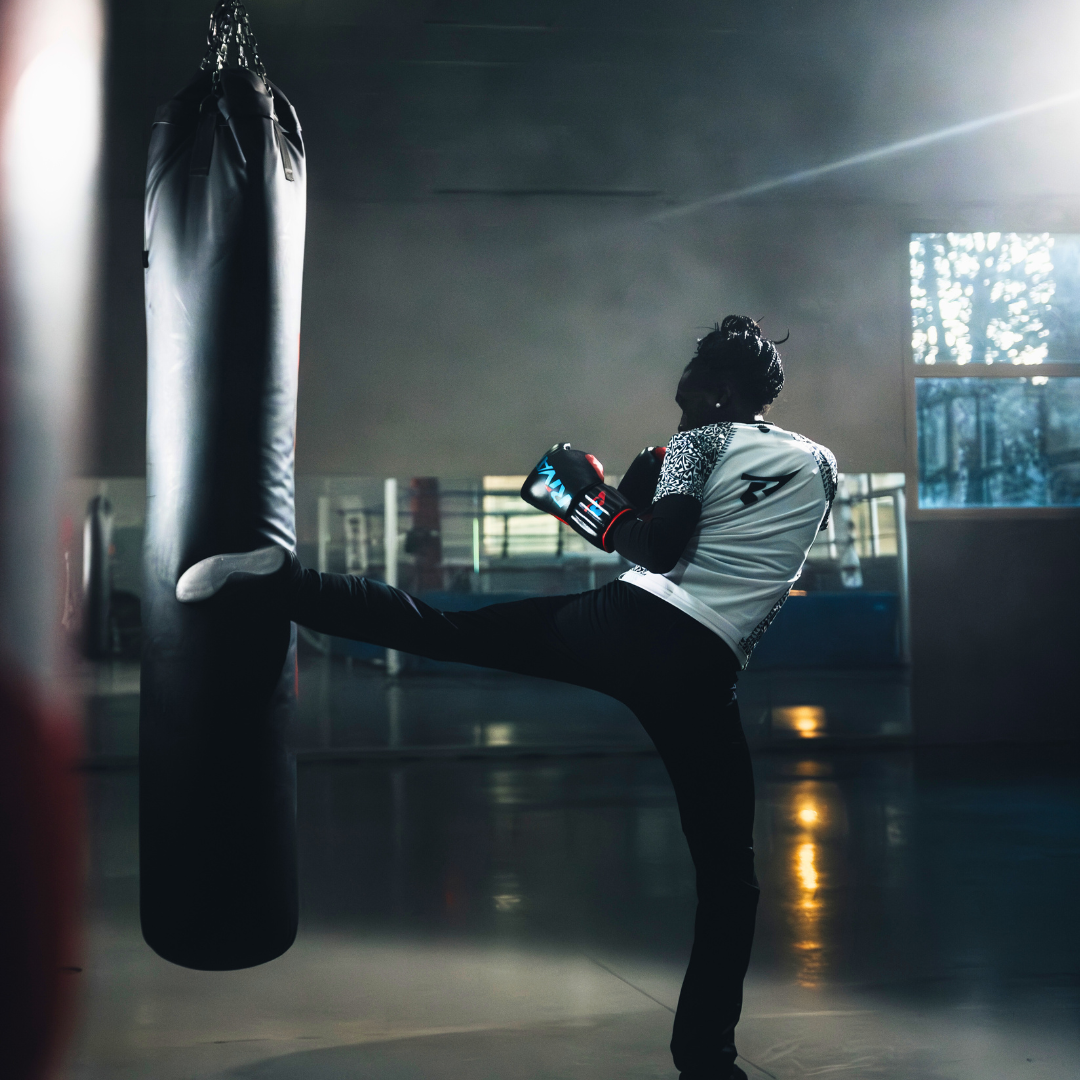 Jeune boxeur en pleine séance d'entraînement boxe française débutant frappant un sac de frappe en salle