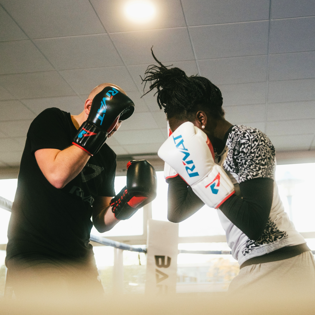 Deux boxeurs en position de garde en boxe française s'entraînant dans un ring lumineux