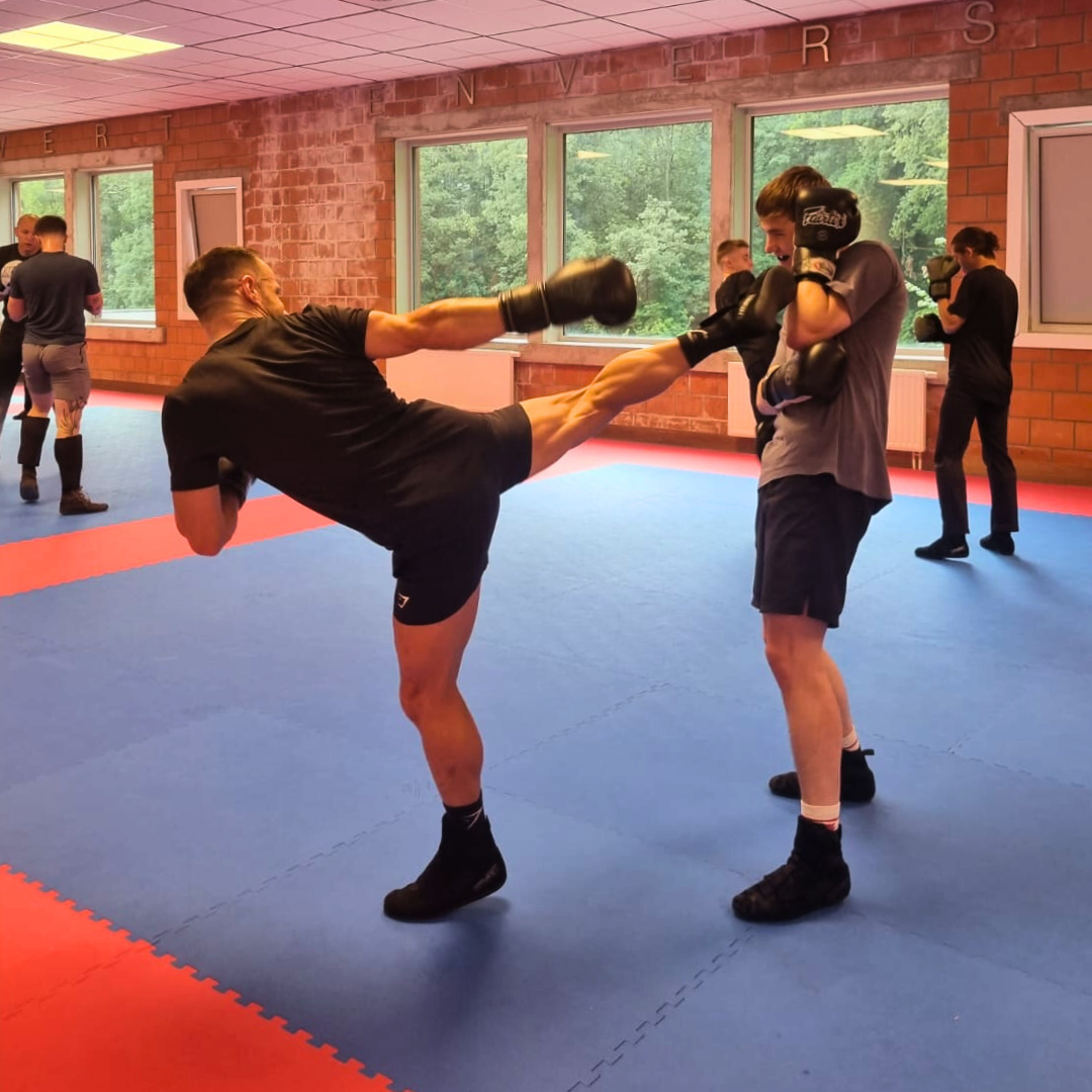 Deux boxeurs pratiquant la technique coup de pied avant boxe française dans une salle d'entraînement