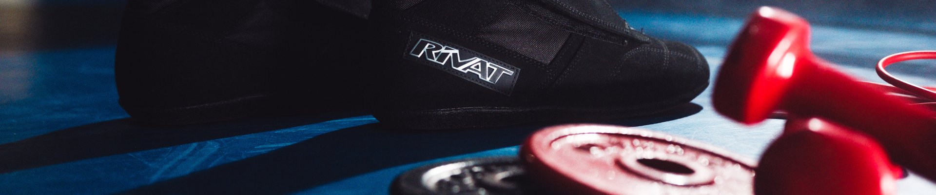 Accessoires boxe française incluant gants rouges, poids et chaussures sur un tapis de ring bleu