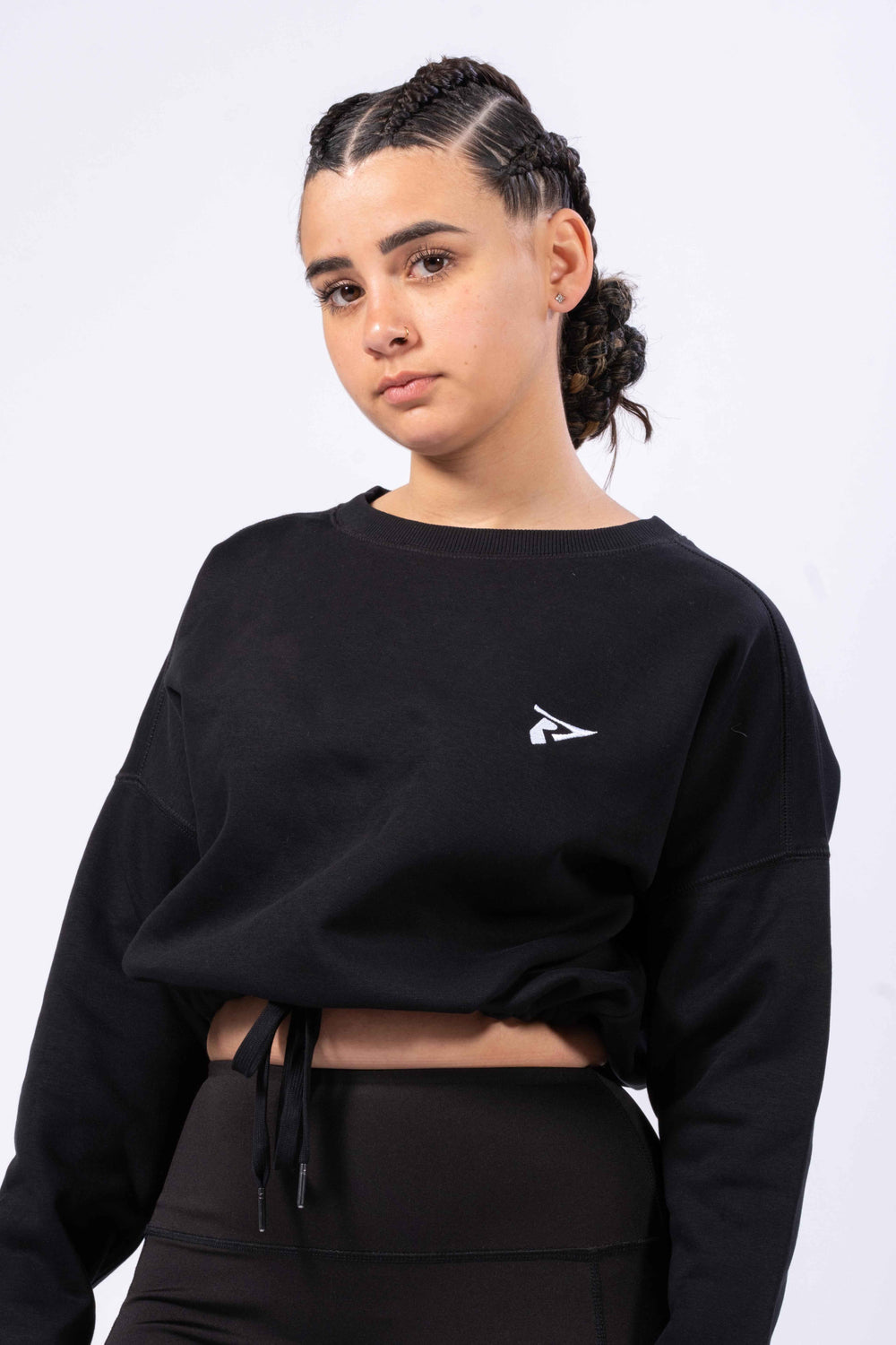 Sweat-shirt crop oversize femme noir Rivat avec logo blanc porté par une femme avec coiffure tressée